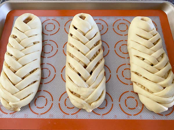 Roll each portion of the dough into 7.5" by 7.5" square. Make creases to divide the square to thirds. Roll the side thirds twice thinner than the center and slice them into 1/2" strips. Make sure you make symmetrical cuts. Use about half of the cup of apple confiture to arrange it down the center. Connect the first strips on both sides to create a border. Then, alternate other stripes over the top of the filling, forming a braid.