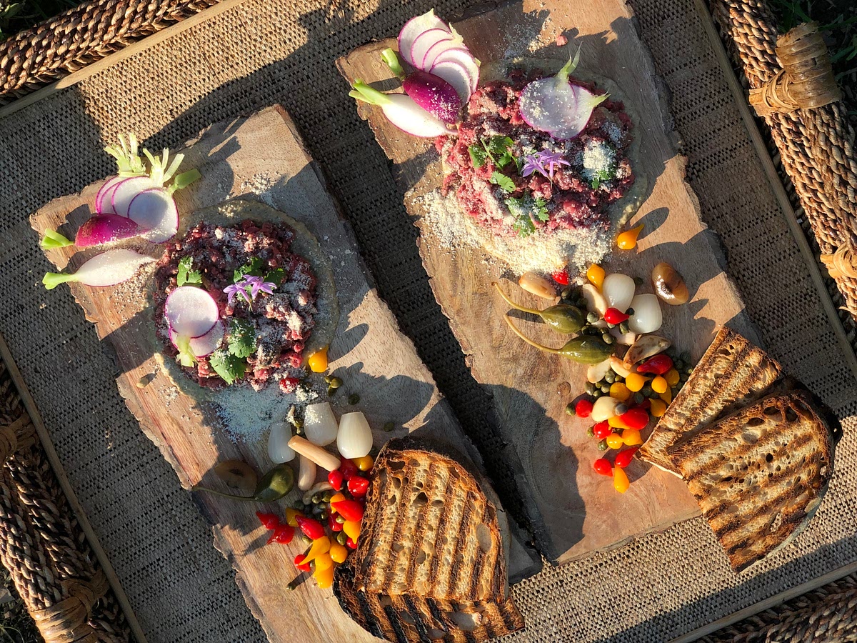 Spread 1 tbsp of the sauce on a serving plate, making a circle. Place a portion of steak tartare on top. Arrange the toppings and bread and serve.