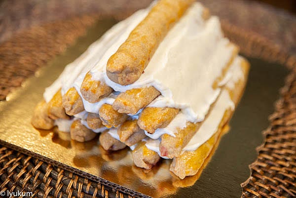 Start with 5 cherry pies on the cake base. Cover them generously with a portion of cream, spreading it with a spatula. Arrange the rest of the pies layering them with cream to make a pyramid as shown in the picture.