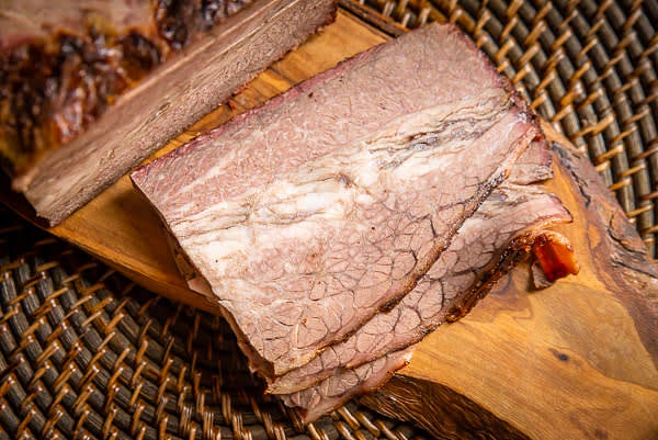 Thinly slice cold brisket, then reheat it. Depending on the number of portions you are serving, it can be done differently. The best way to reheat 1-2 slices is by using the microwave — power level 5-6, 1-2 minutes, covered.