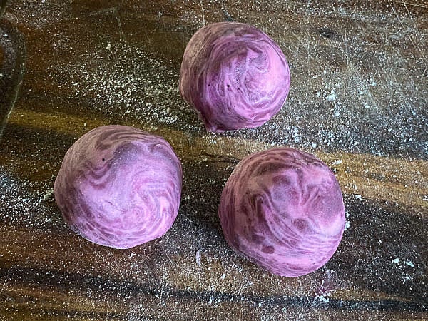 To shape pastries, flatten every portion of dough 0.1 inches thin and wrap it around the taro stuffing. Pinch the dough to secure the seam. Arrange shaped pastries on the baking sheet.