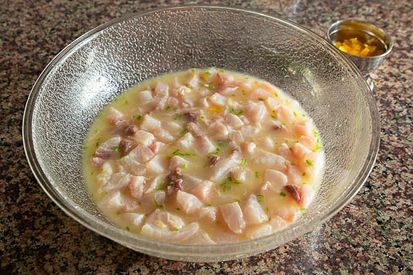 In a bowl, combine citrus juices, salt, and serrano. Add cubed fish. Make sure fish is completely submerged into the marinade. Refrigerate for 30 minutes.