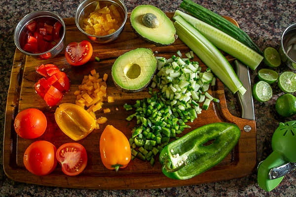 Prepare vegetables. Wash them. Remove seeds and dice the tomatoes. Half chili peppers, remove seeds and membranes, dice them. Peel and dice onions and scallions.