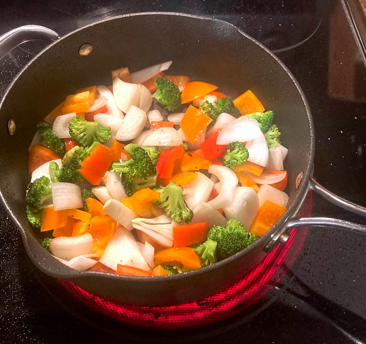 Swirl in remaining vegetable oil and add broccoli. Cook, stirring occasionally, until broccoli begins to brown, about 3 minutes. Add the reserved water, onion, and pepper, and toss until broccoli is bright green and tender, 1 to 2 minutes more.