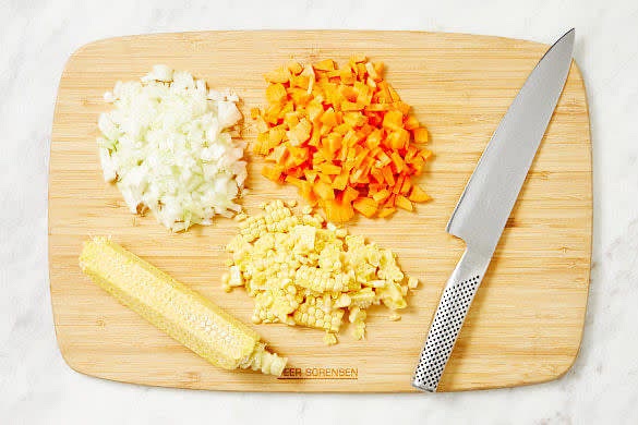 Meanwhile, crush or finely chop the garlic. Finely chop the onion. Finely chop the carrots. Discard the husks and silks from the corn. Slice the corn kernels from the cobs.