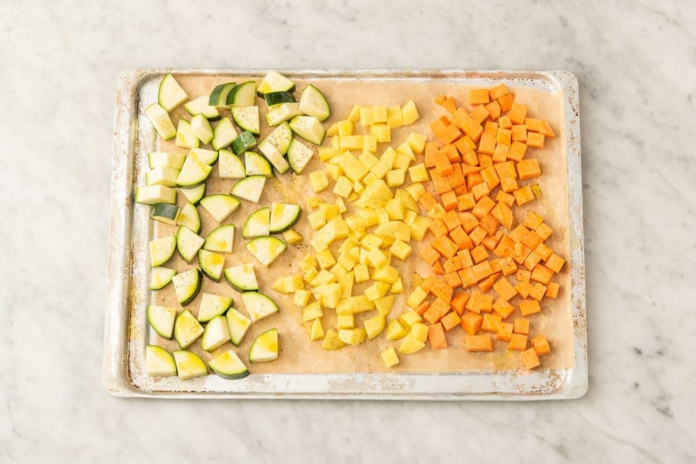 Kartoffelwürfel, Zucchinistücke und Süßkartoffelwürfel auf einem mit Backpapier belegten Backblech verteilen, mit 1el [1,5el|2el] Olivenöl beträufeln und mit Salz* und Pfeffer* würzen.