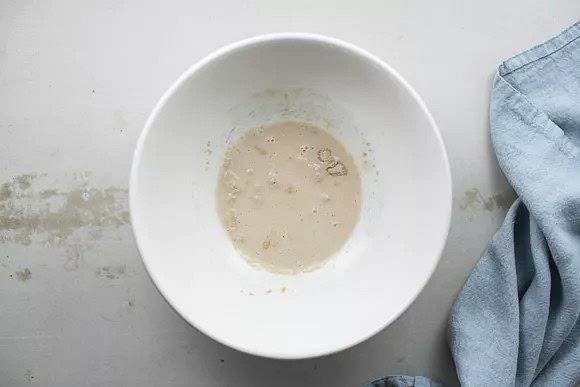 Stir the yeast and the warm water together in a large bowl and allow the yeast to dissolve for 5 minutes. Lightly beat the eggs into the yeast and water.