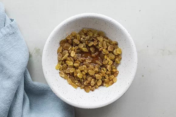 Meanwhile, soak the raisins or currants in 3 tablespoons of rum. Once the dough has doubled, beat the rum-soaked fruit into it.