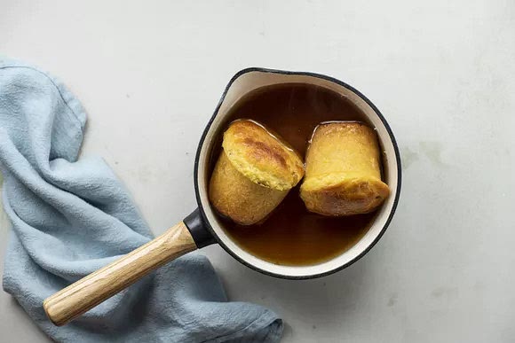 Place the babas into the hot rum syrup in batches, turning them several times, allowing them to soak up the syrup. They will swell and absorb most of the syrup. Continue to soak the babas until all the syrup is used.