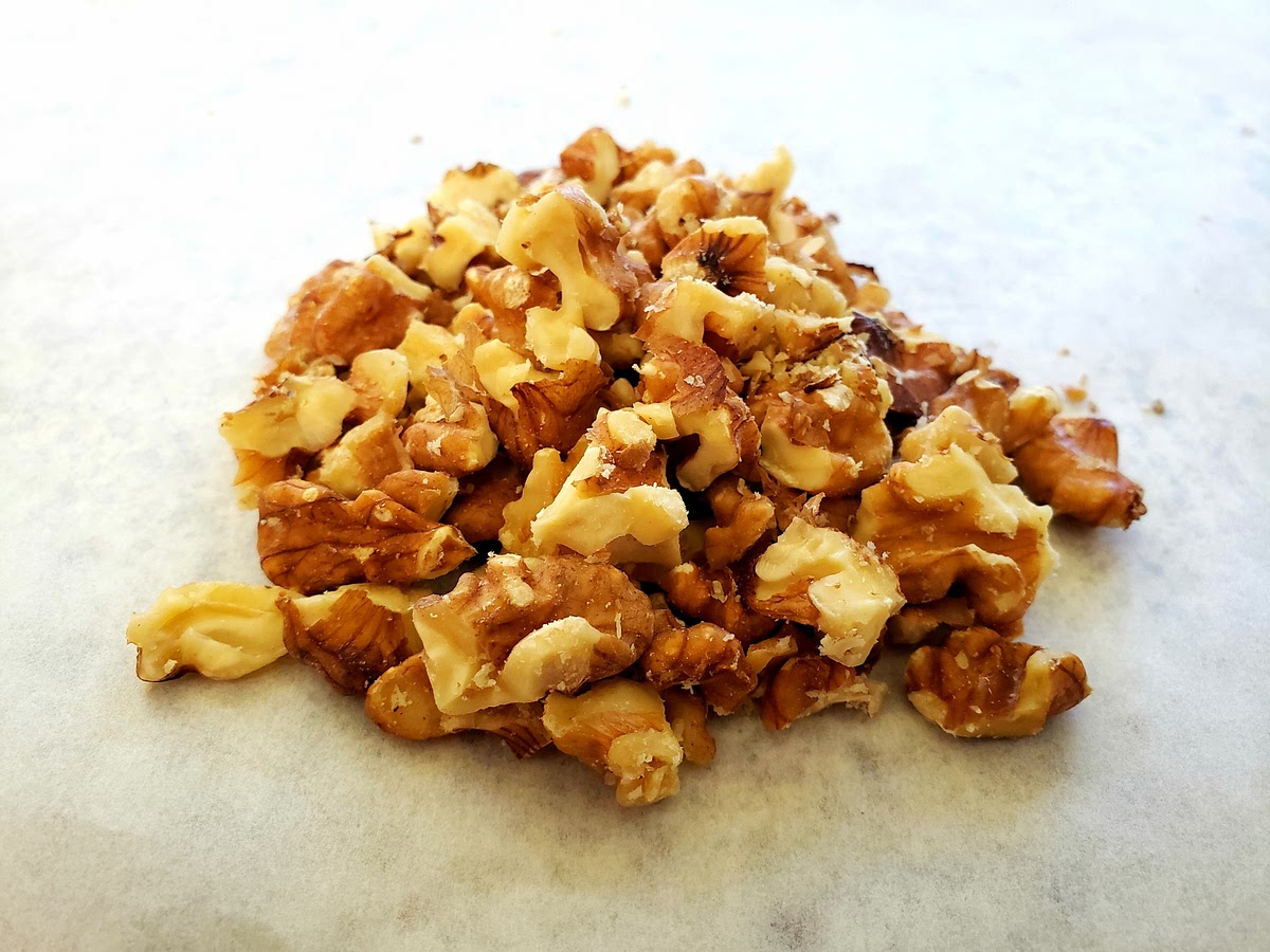 Line one baking pan with parchment paper put walnuts on paper being sure to spread them out evenly. Bake at 150c or 300f for 10 min or until lightly browned (be sure they are cut up first) then place in bowl with lid shaking to remove hulls. Place walnut back on parchment paper and over sink lightly blow hulls off of pan. Now they are ready to use
