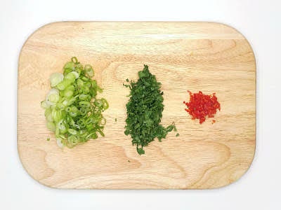 Trim, then slice the spring onions Chop the coriander finely, including the stalks Cut the red chilli[es] in half lengthways, deseed (scrape the seeds out with a teaspoon) and chop finely