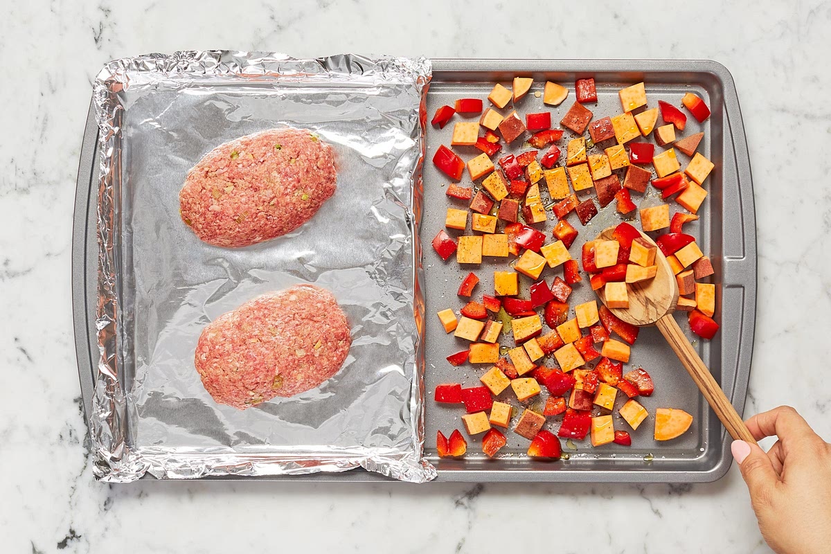 Add sweet potatoes and bell pepper to unlined side of same sheet; toss with a large drizzle of oil, salt, and pepper. (For 4 servings, toss veggies on a second sheet; roast meatloaves on top rack and veggies on middle rack.) • Roast on top rack until meatloaves are browned and veggies are slightly tender, 20 minutes. (The meatloaves and veggies will finish cooking in step 5.)