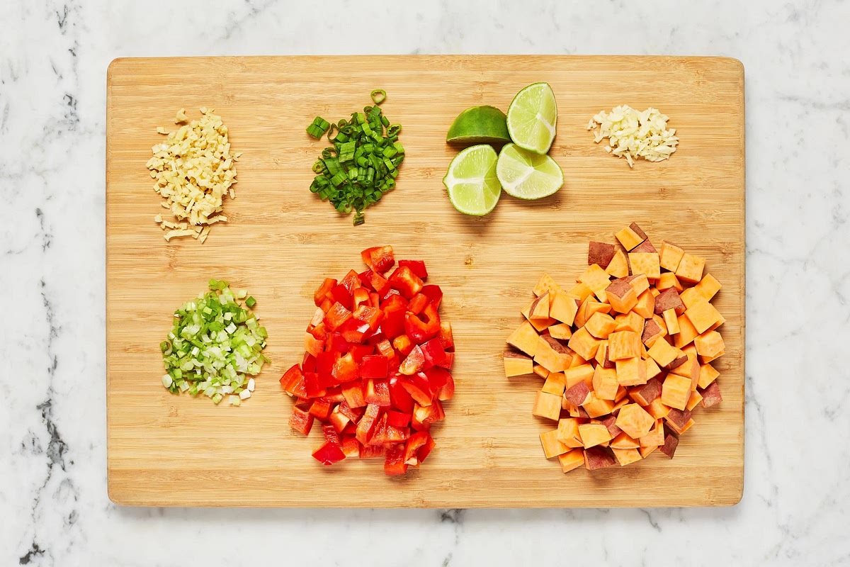 Adjust rack to top position (top and middle positions for 4 servings) and preheat oven to 425 degrees. Wash and dry produce. • Trim and thinly slice scallions, separating whites from greens; mince whites. Peel and mince or grate garlic and ginger. Dice sweet potatoes into ½-inch pieces. Core, deseed, and dice bell pepper into ½-inch pieces. Quarter lime.