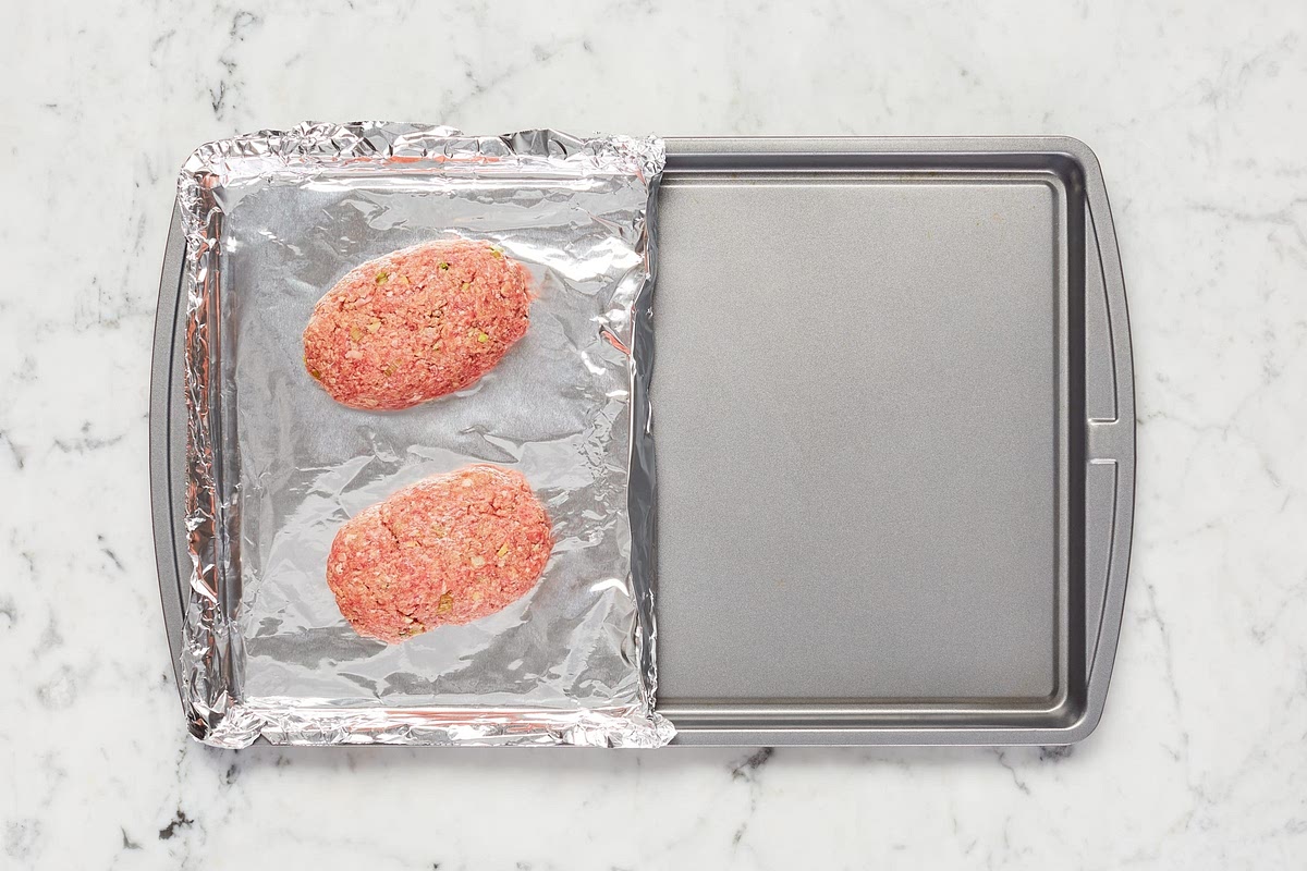 In a large bowl, combine beef*, panko, ponzu, scallion whites, garlic, and ginger. Season with salt (we used ½ tsp; 1 tsp for 4 servings) and pepper. Form mixture into two 1-inch-tall loaves (four loaves for 4). • Line one side of a baking sheet with foil and lightly oil; place loaves on foillined side. (For 4, line whole sheet; spread out loaves across entire sheet.) Fold up a bit of foil to create a barrier in the middle of the sheet. TIP: Don’t have foil on hand? Roast meatloaves and veggies on separate sheets.