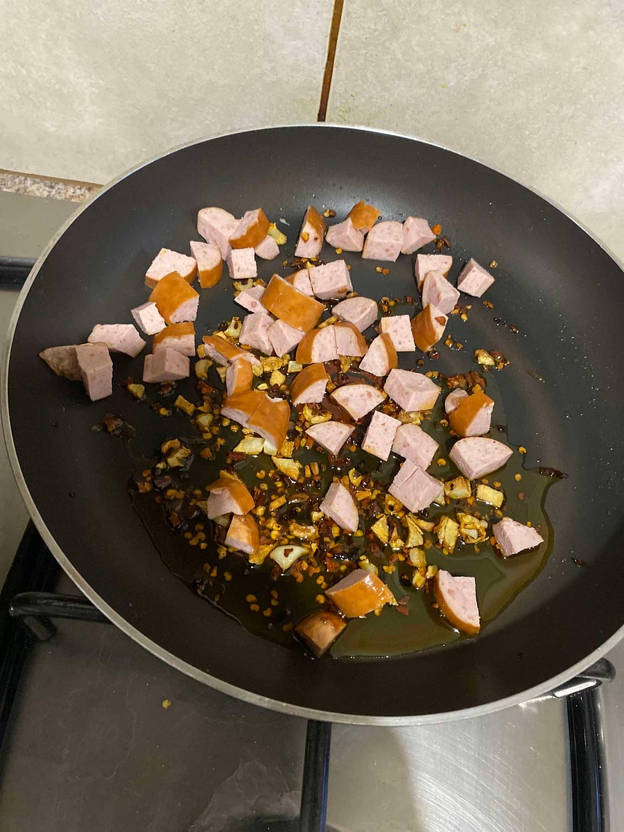 While the spaghetti cooks pour oil in a pan and add chopped garlic, pieces of sausage, chilli flakes and any seasoning of your choice