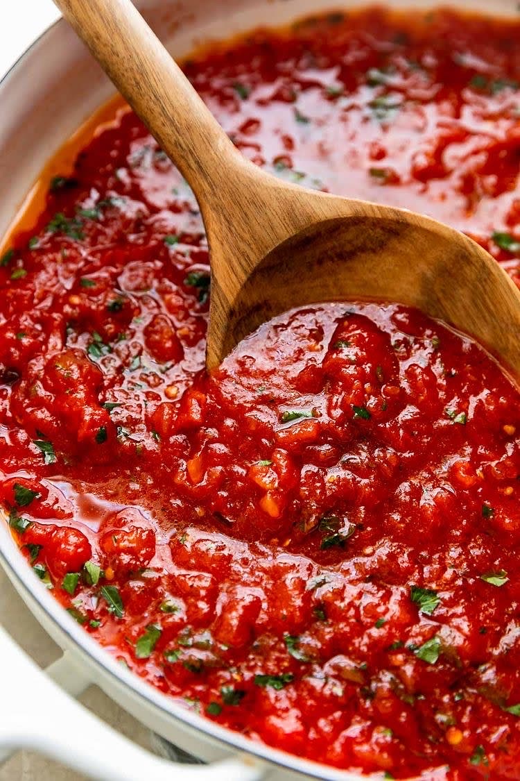Dejar caer los dientes de ajo en el aceite caliente. Una vez dorados, dejar caer los tomates y agregarle sal al gusto. Dejar que se cosan por unos 2-3 minutos y luego machucar los tomates hasta que se forme una salsa. Dejar hervir por 6-8 minutos y en los dos últimos minutos, agregar la albahaca para darle más sabor.