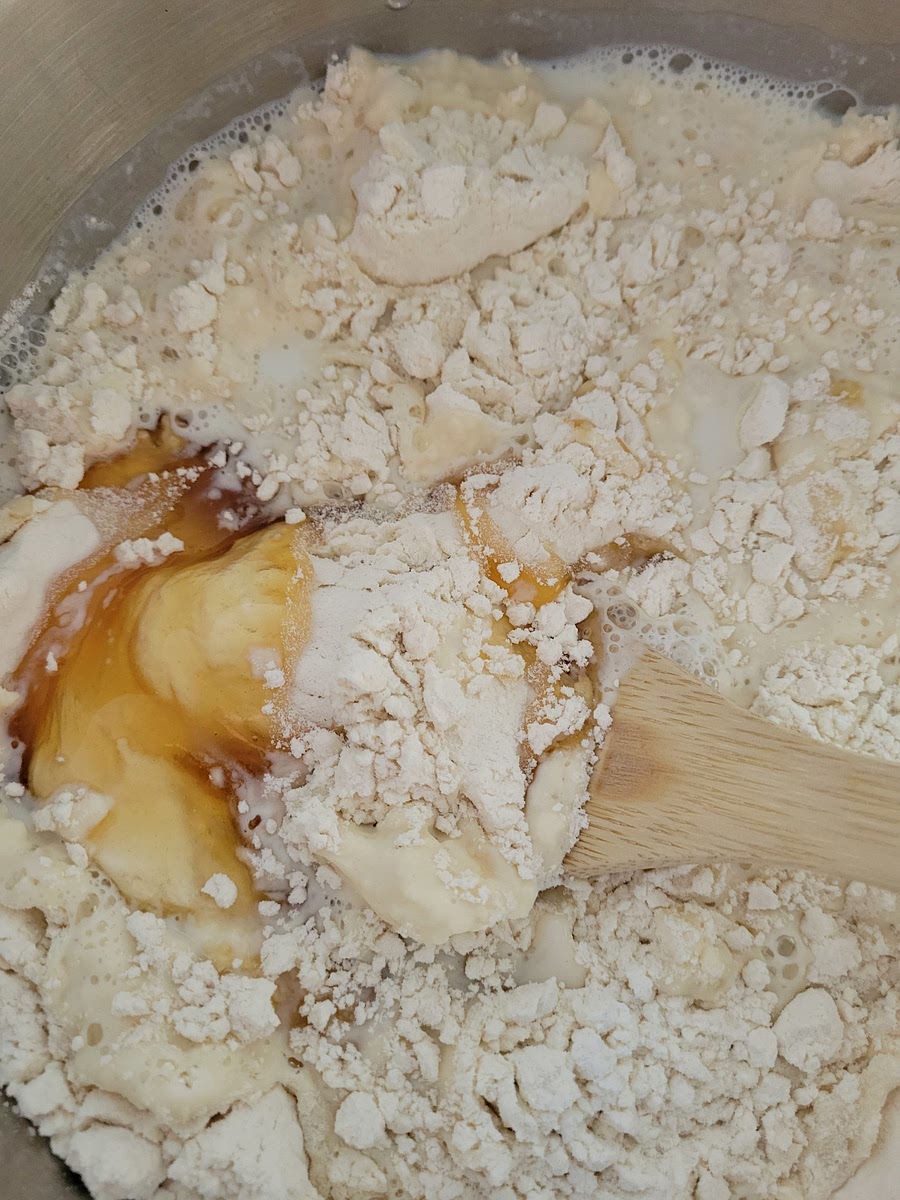 ADD REMAINING SUGAR, HONEY, MILK, AND 3 1/2 CUPS OF FLOUR TO THE YEAST MIXTURE. MIX TOGETHER FOR A COUPLE OF MINUTES.