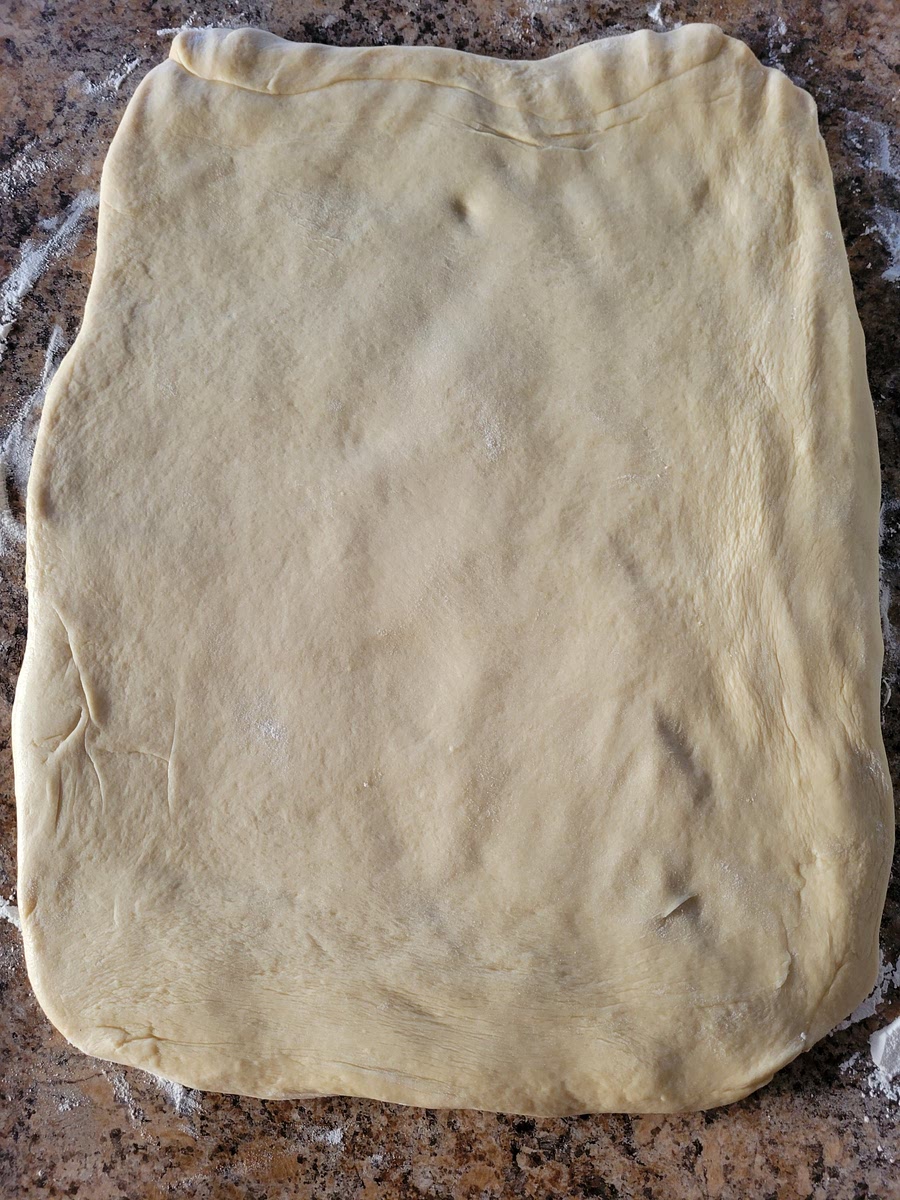 ONCE THE DOUGH HAS DOUBLED, PUNCH IT DOWN TO RELEASE THE AIR. EMPTY DOUGH ONTO A LIGHTLY FLOURED WORK SURFACE. USING A ROLLING PIN, ROLL THE DOUGH OUT TILL IT IS ABOUT 1/2-INCH THICK.