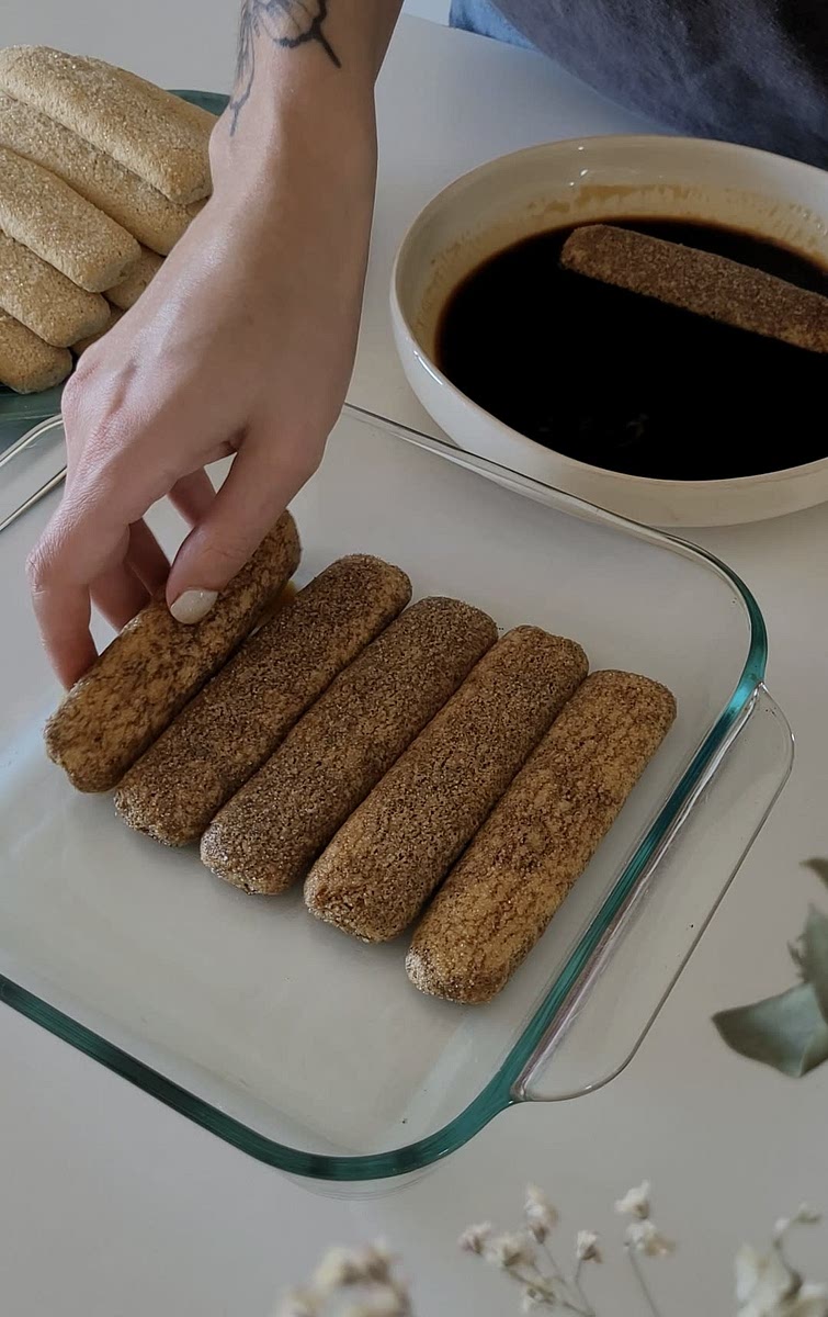 Embeber las galletas vainillas en el café y cubrir la base de la fuente, poner por arriba la mitad de la mezcla anterior, y repetir el proceso una vez más
