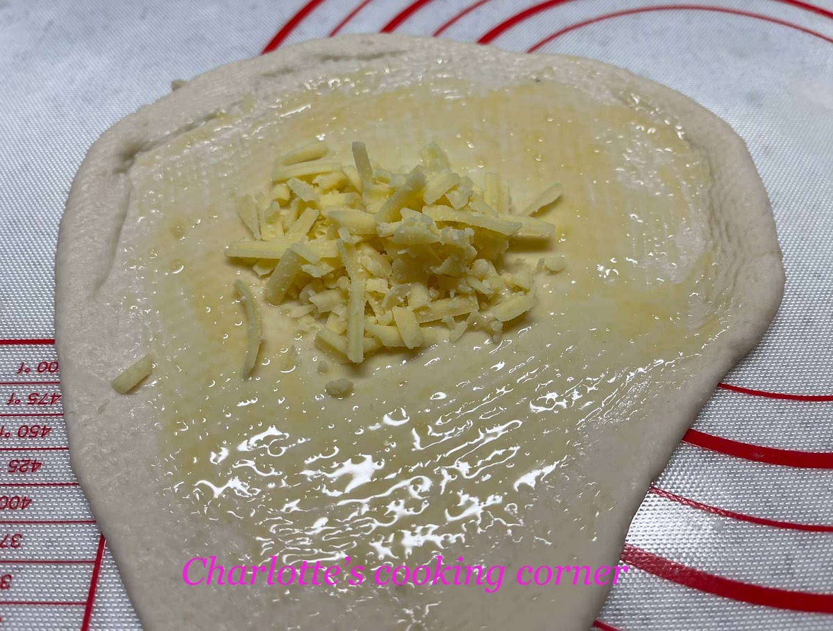 With the rolling pin, roll the dough into 3-4 mm thick and brush the garlic butter on. Add in a mound of cheese.