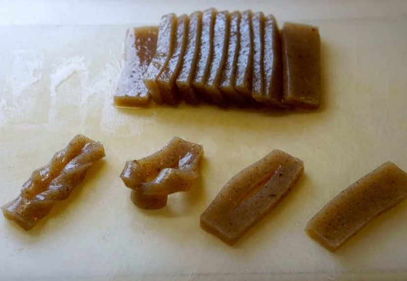 Drain the excess water from the package of konnyaku and rinse it under running water. Cut into 7-8mm thick slices and cut a slit inside of each slice, lengthwise. Pull one end of the slice through the slit, twisting it into the tazuna shape. Do the same for the rest of the slices.