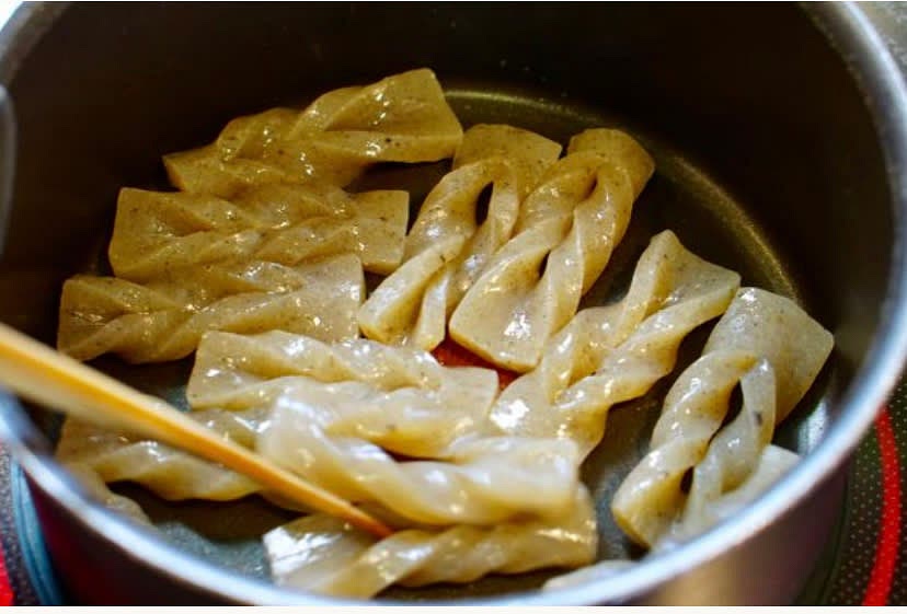 Put the konnyaku twists in a pot and heat over high to further remove the moisture, flipping the twists after a minute or two.