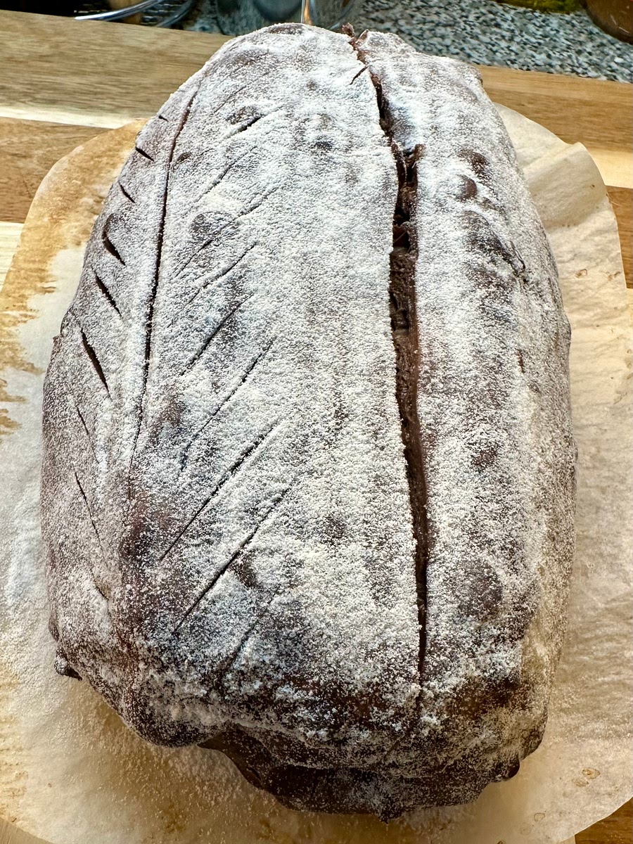 The next day, preheat your oven and cast iron pan to 450°F for about 60 minutes. Turn your loaf out of the Banneton onto parchment, dust the top with rice flour so your pattern will show, and slash the dough (deeper functional and optional decorative shallow cuts).