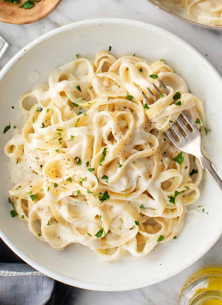 Melt butter in a medium, non-stick saucepan over medium heat. Add cream cheese and garlic powder, stirring with a wire whisk until smooth. Add milk, a little at a time, whisking to smooth out any lumps. Stir in Parmesan cheese and pepper.