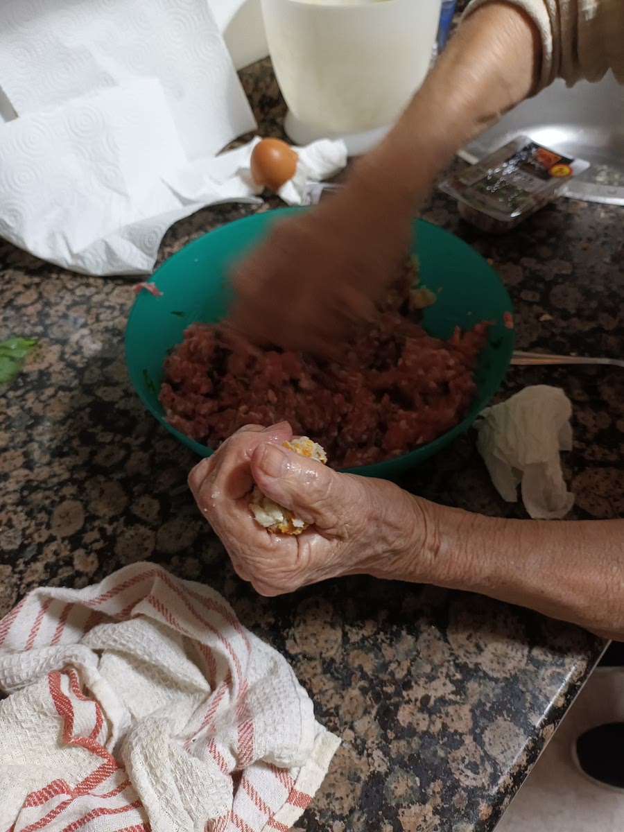 Echamos el jamón, una pizca de sal, el pan rallado, y trocitos de pan, preferentemente que sea de ayer. Si no se desmorona lo mojamos. Echamos también el 2° huevo. Luego, movemos con las manos.