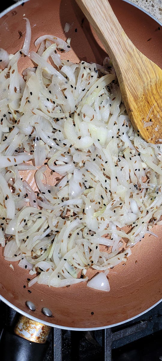 After jeera starts cracking, add in onions and garlic. Sautee them till they are translucent but not browned.