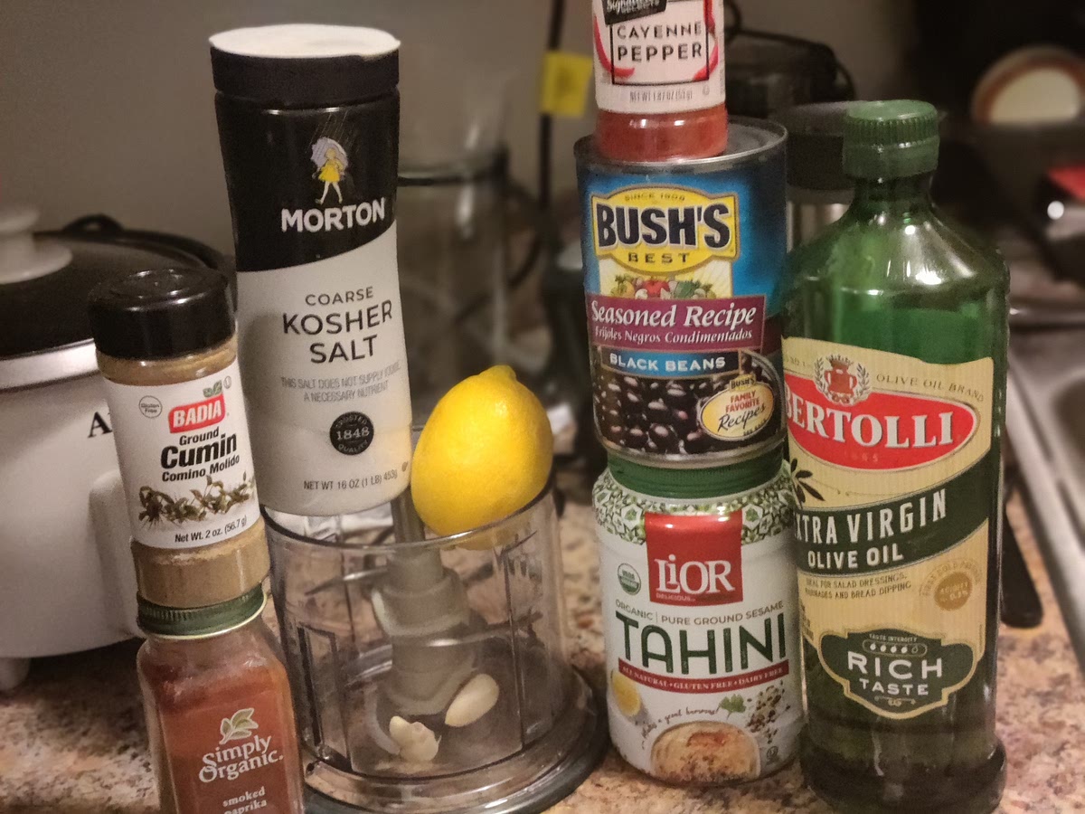 add garlic to food processor, mince
add black beans, lemon juice, tahini, cumin , salt, and , cayenne pepper. Pulse processor, process until smooth.