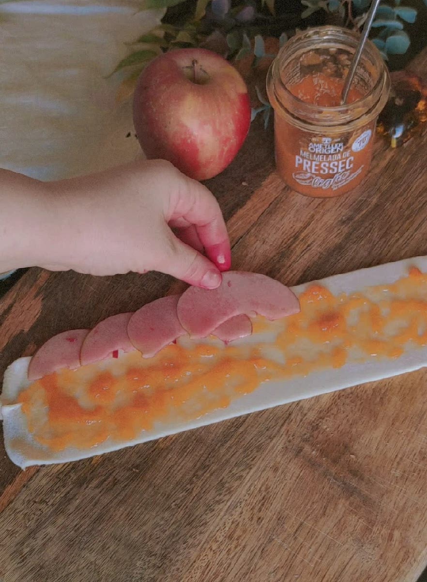 6) Position the apple slices on the top like the video and fold the pastry in half. Then, roll it until you have the rose.