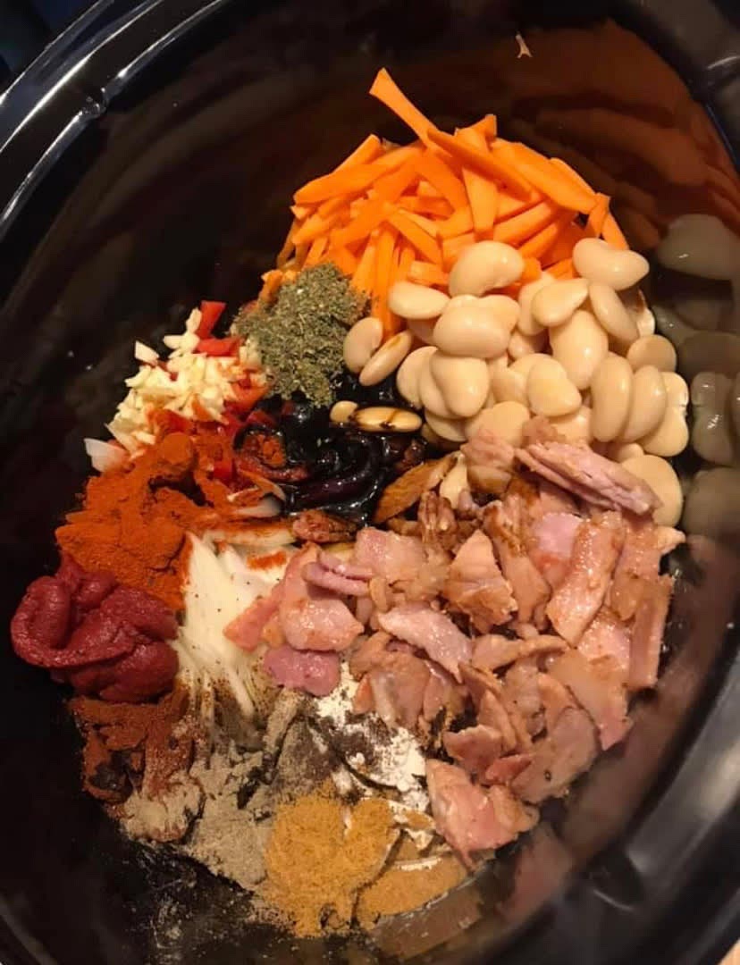 Put everything except the bacon and sausages into the slow cooker. stir through to mix and put the sausages on top.
