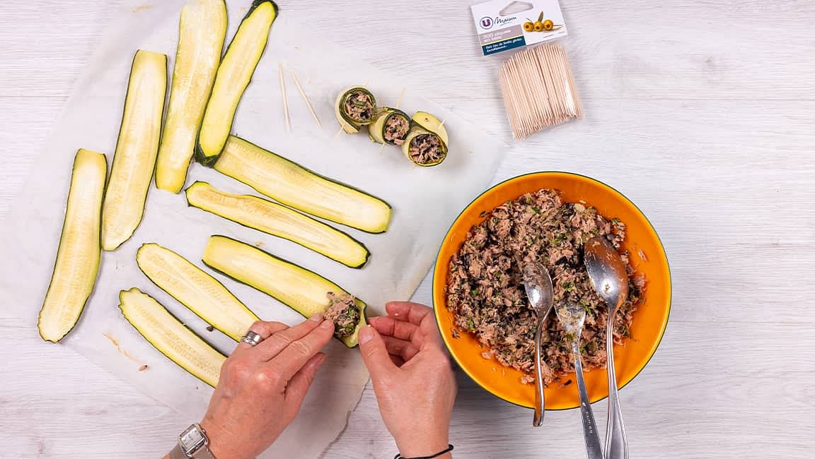 Prélevez l’équivalent d’une grosse noix de la préparation au thon et déposez-la sur une tranche de courgette. Roulez et maintenez le tout avec une pique en bois. Décorez de quelques feuilles de basilic.