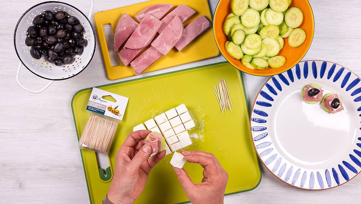 Égouttez les rondelles de concombre et montez les canapés : assemblez une rondelle de concombre, une lamelle de jambon pliée en accordéon, un dé de feta et une olive. Fixez le tout à l’aide d’une pique en bois. Répétez l’opération jusqu’à épuisement des ingrédients.