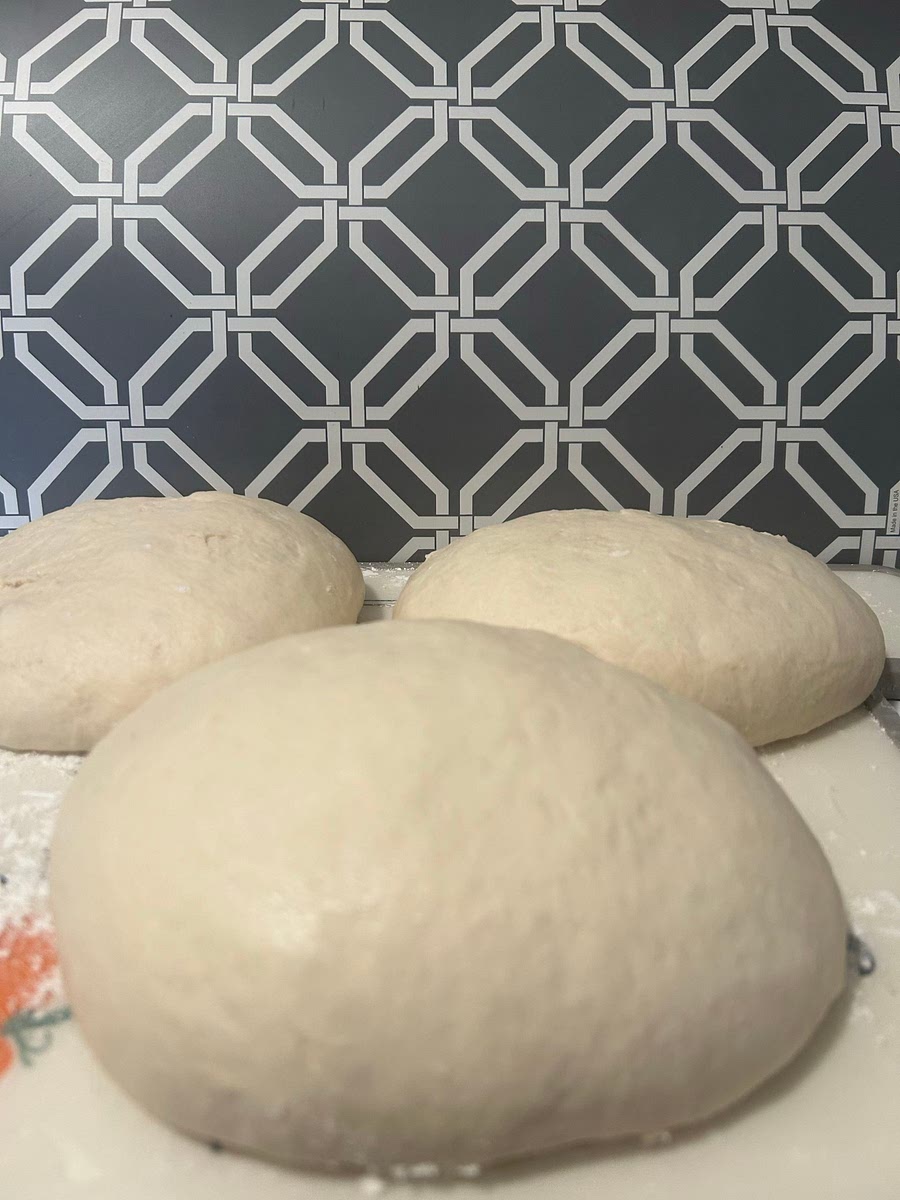 1) Combine water, sugar, and yeast. Allow to foam up - about 5 minutes.
2) Mix flours and salt in a heavy duty bowl or stand mixer fitted with a dough hook.
3) Add oil to yeast mixture. Pour yeast mixture into flour mixture and knead on low speed for 10 minutes. Dough will be elastic and lightly sticky.
4) Place dough in a lightly oiled bowl, turning to coat.
5) Cover with plastic wrap and let rise in a warm place for an hour. Punch dough down and divide into 3 pieces.
6) Shape into balls and place on floured work surface. Brush with oil and cover with plastic wrap for 45 minutes.
7) Shape into thin layer on pizza stone and add sauce, cheese, etc. and bake at 425 for 12-14 minutes depending on toppings. Original recipe makes three 10 inch pizzas.