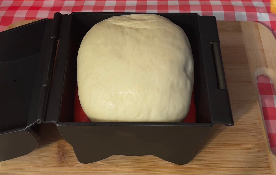 Grab the white dough and stretch it out slightly. Place it on top of the coloured dough. Cover the mold with plastic film and proof for 40-60 mins until doubled in size.
