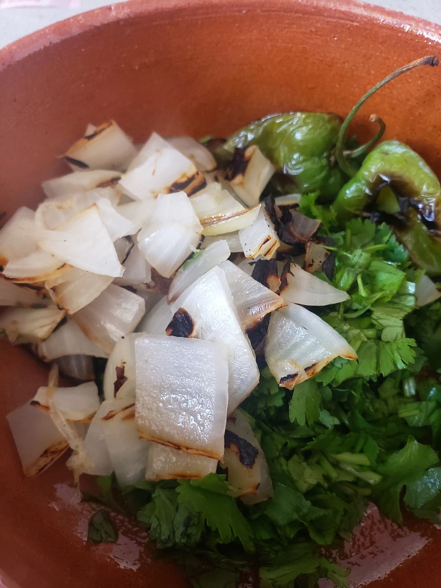 Picar el cilantro y la cebolla tatemada, y añadir en la salsera los chiles habaneros