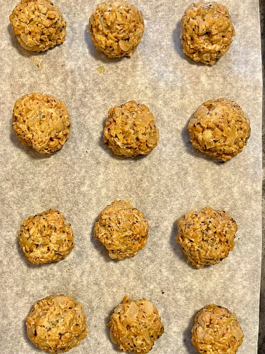 Once the dough is cool enough to handle, wet your hands (to prevent sticking), then take about 2 tablespoons of dough and gently roll it into a meatball and place it on the prepared baking sheet. I like to use a 2 tablespoon capacity cookie scoop to make this process super quick. Repeat to make about 14 meatballs. Space the meatballs out on the baking sheet so they aren't touching and lightly spray or brush the tops with a bit of oil.