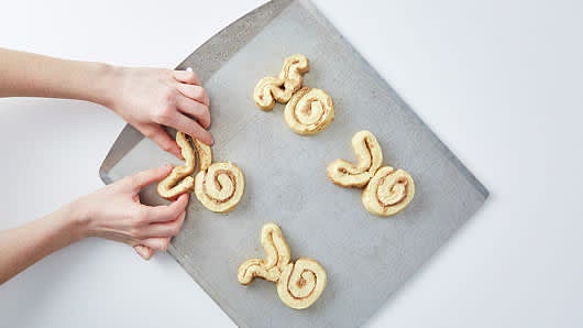 Place 4 rolls on cookie sheet, about 3 inches apart. Unwind remaining 4 rolls into long dough strips. For each bunny, place one dough strip, cut ends together, next to a whole roll. Press and firmly pinch cut ends into top of whole roll. Shape strip into floppy bunny ears.
