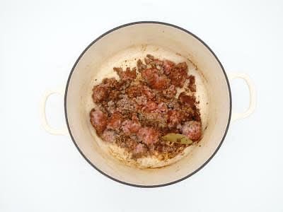 Add the lamb mince to the dish with the dried oregano, bay leaf[ves] and baharat and cook for 1-2 min, breaking the mince into rough, large chunks until very lightly browned all over