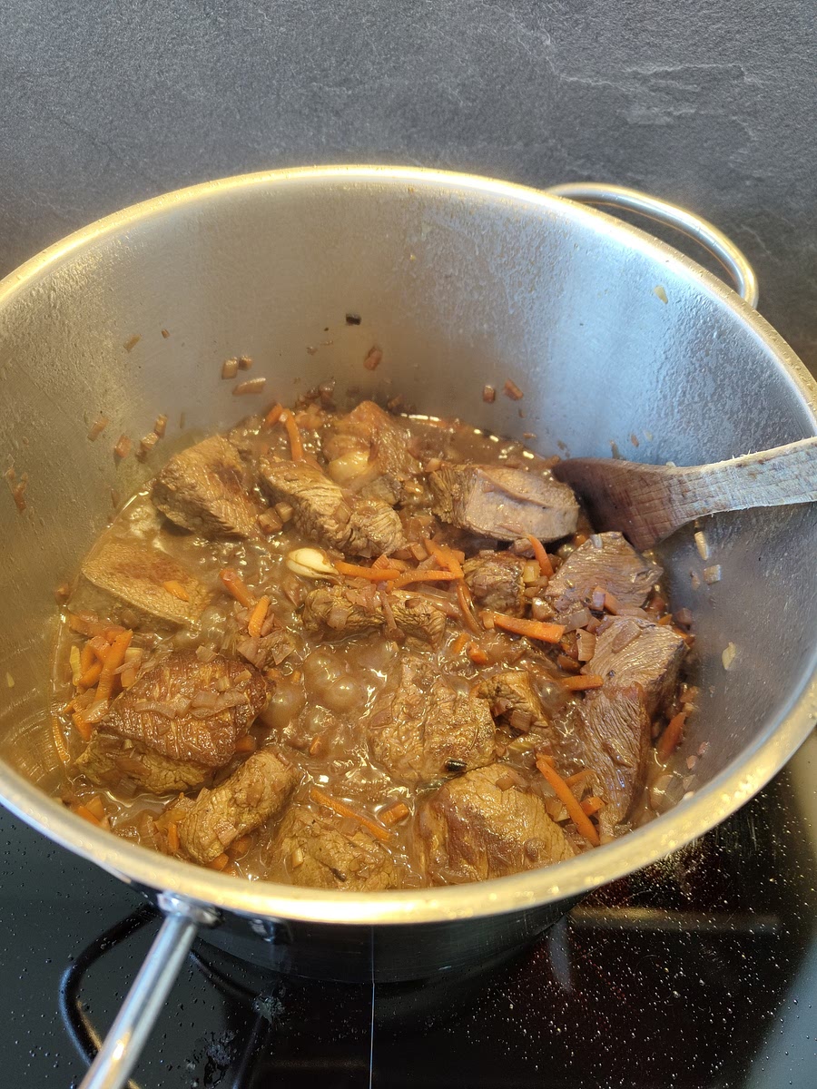 Déglacer avec le vin rouge, laisser bouillir 5min et rajouter la viande.