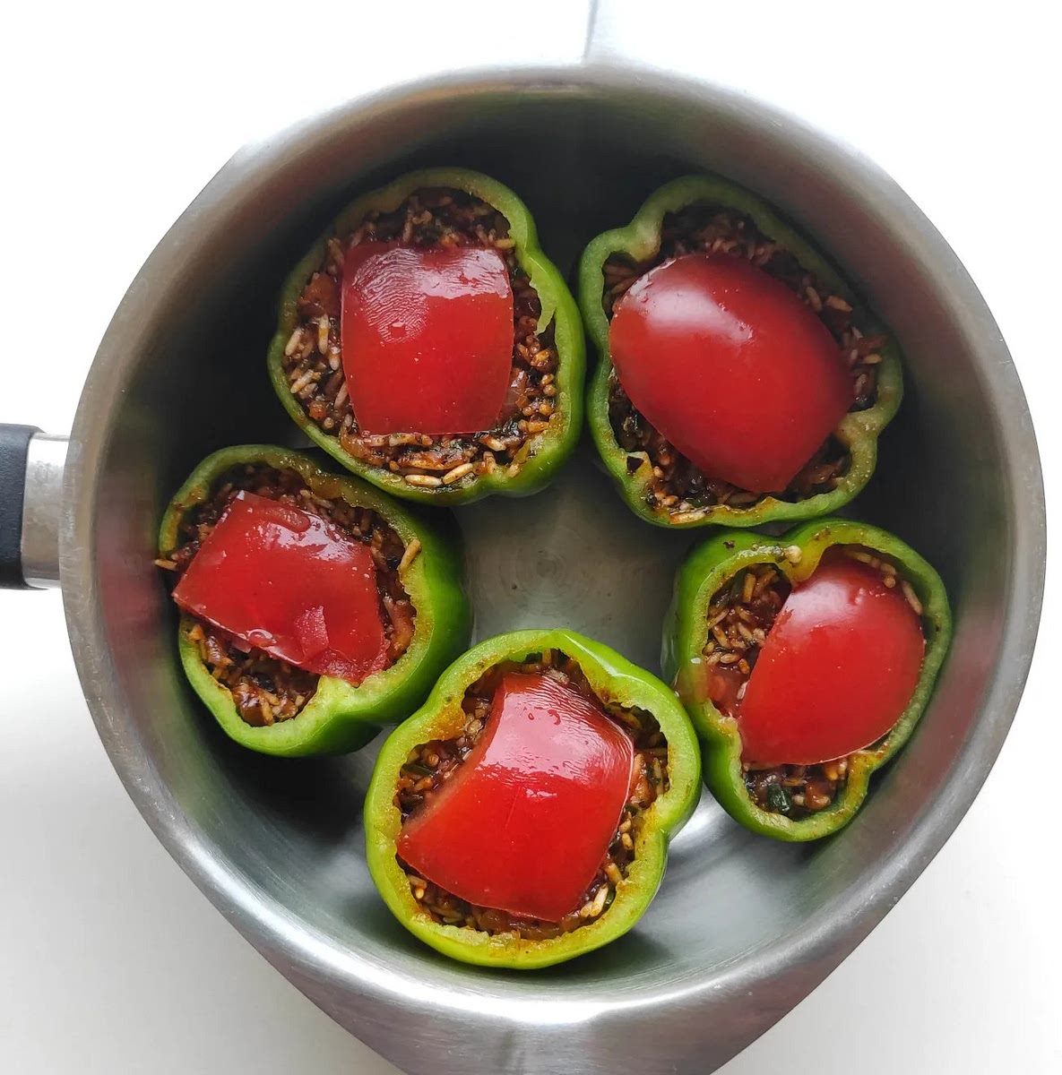 Place the stuffed bell peppers in a small pot and place a piece of tomato on the filling.