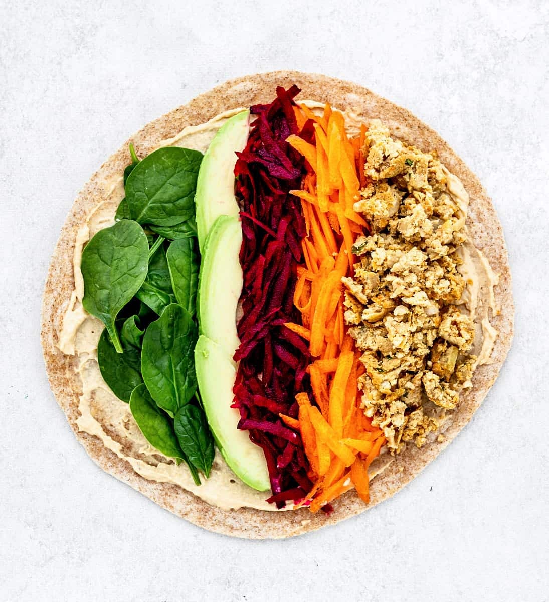 Next, place on the toppings for the falafel wrap. Line each of the ingredients in equal strips across the wrap.