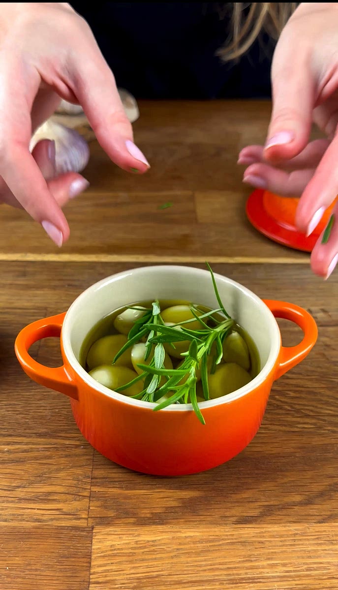 * Drizzle enough olive oil over the garlic cloves to cover them, and add 2 sprigs of rosemary. Cover the dish with a lid or aluminium foil.