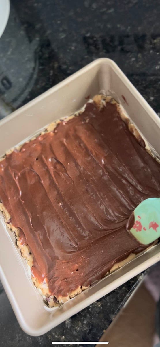 Pour some of the brownie batter over the cookie dough, covering it completely. Spread evenly.