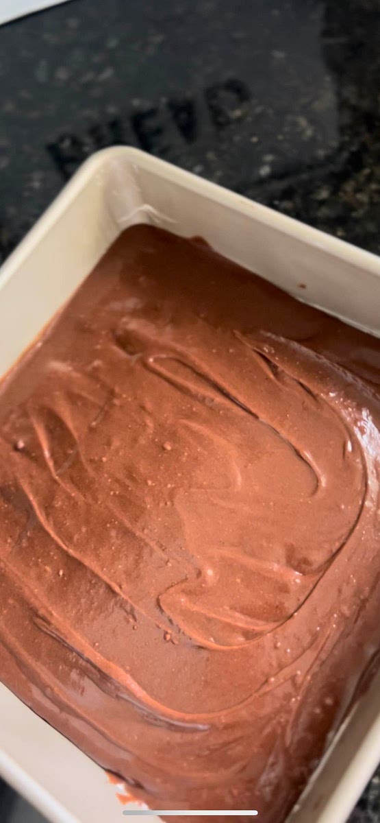 Pour the remaining brownie batter over the Ghirardelli squares, ensuring they are fully covered.