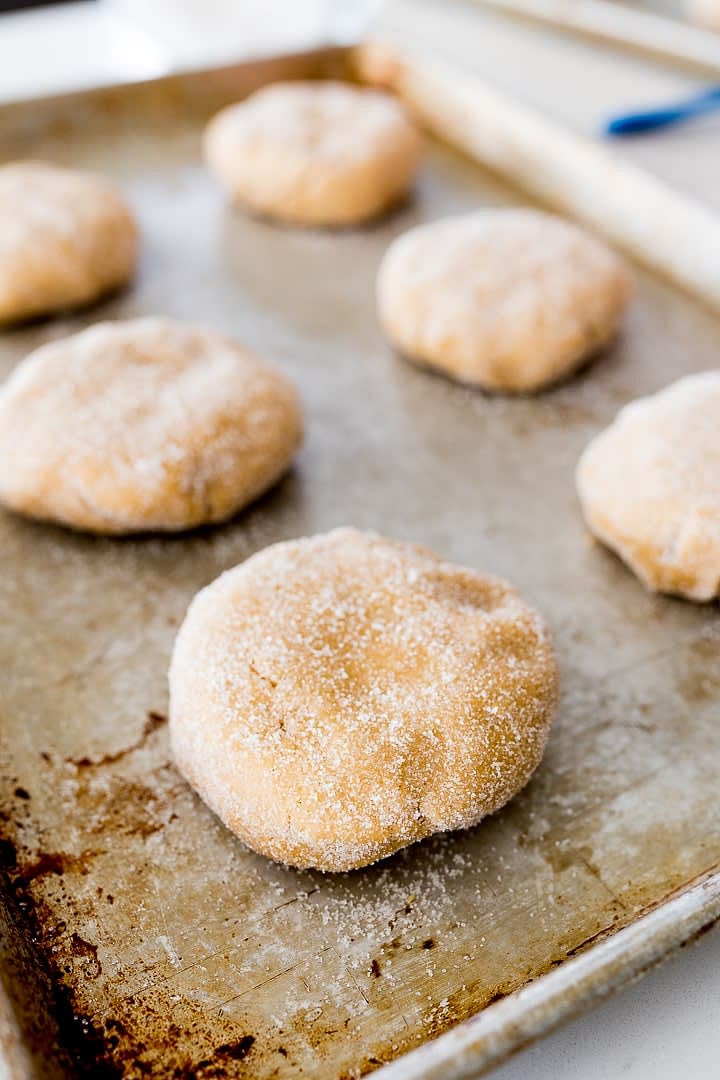 Vierte los últimos 100g de azúcar en un tazón y presiona cada una de las bolas de masa para que se cubran uniformemente con el azúcar.