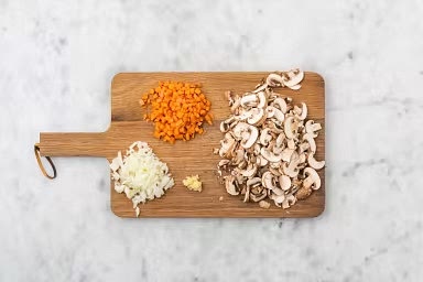 Nettoyez les champignons à l’essuie-tout, puis coupez-les en lamelles. Coupez les carottes en petits morceaux. Émincez l’oignon. Émincez ou écrasez l’ail.