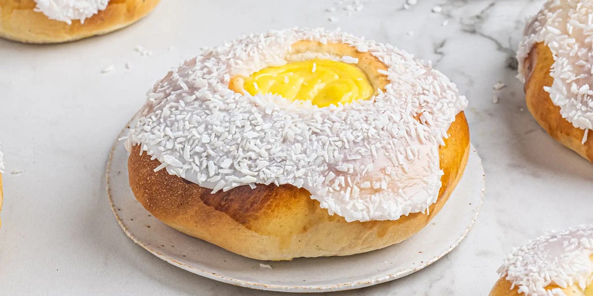 Mixe Puderzucker und Wasser, bestreiche die Boller am Rand damit und tauche sie in die Kokosraspel ein.